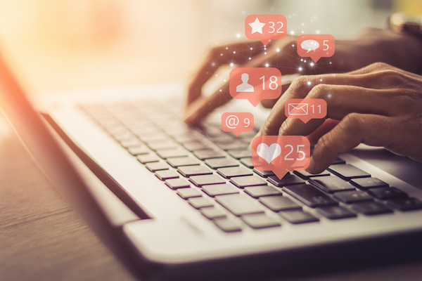 Businesswoman typing on computer with social media notifications