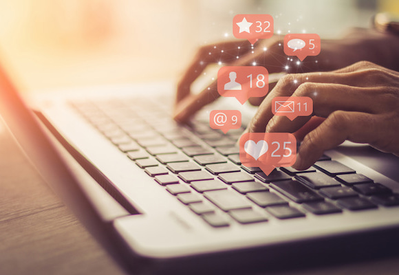 Businesswoman typing on computer with social media notifications