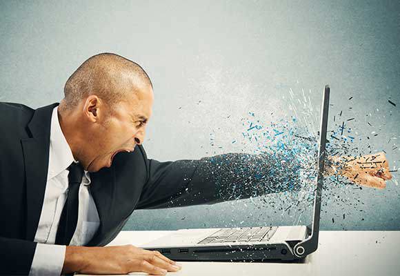 Website owner in suit and tie punching through his laptop screen.